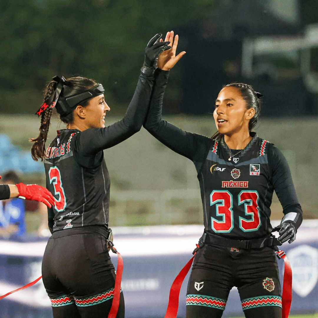 Two female flag footballers celebrate during a game